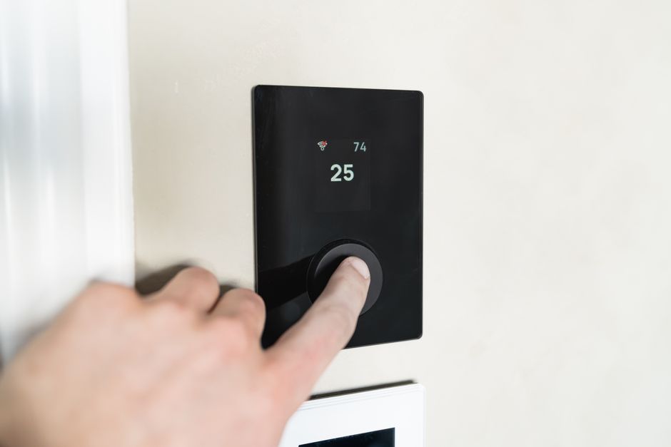 Homeowner adjusting a modern smart thermostat